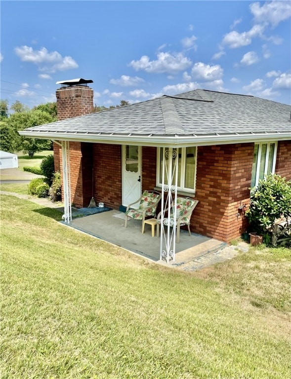 rear view of house with a patio and a lawn