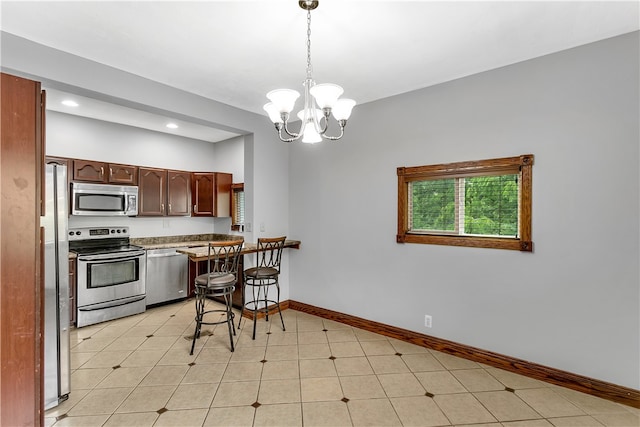 kitchen featuring stainless steel appliances, an inviting chandelier, pendant lighting, and light tile patterned flooring