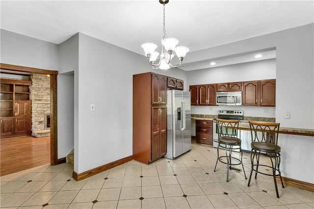 kitchen featuring kitchen peninsula, appliances with stainless steel finishes, an inviting chandelier, light wood-type flooring, and pendant lighting