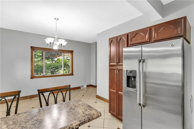 kitchen featuring a notable chandelier, stainless steel fridge, hanging light fixtures, and light tile patterned floors