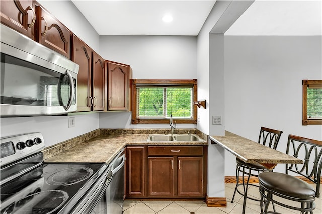 kitchen featuring sink, a kitchen bar, stainless steel appliances, and light tile patterned floors