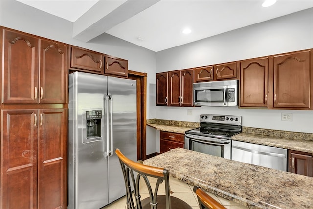 kitchen featuring light tile patterned flooring, light stone countertops, and stainless steel appliances