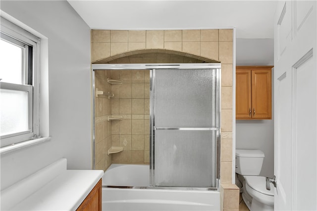 full bathroom with vanity, bath / shower combo with glass door, and toilet