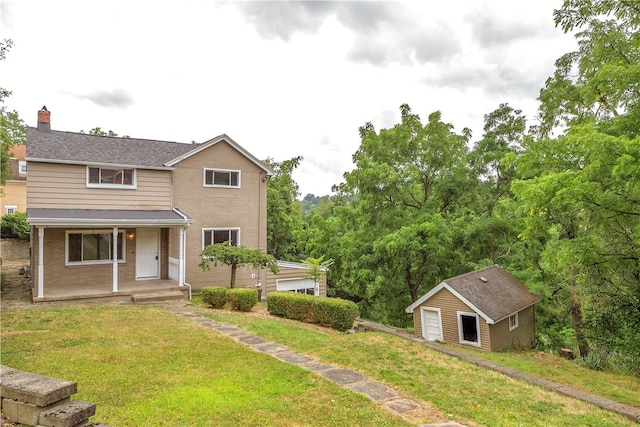 view of front of house featuring an outdoor structure, a garage, a front lawn, and a porch