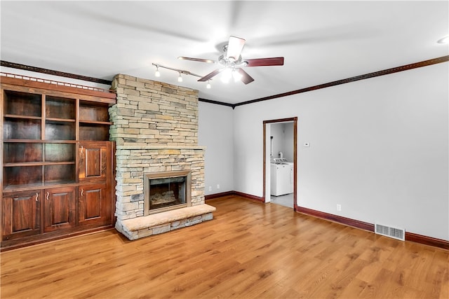 unfurnished living room featuring ceiling fan, a fireplace, light hardwood / wood-style floors, crown molding, and washer and clothes dryer