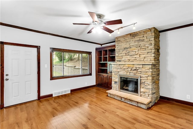 unfurnished living room featuring ornamental molding, a fireplace, light wood-type flooring, and ceiling fan