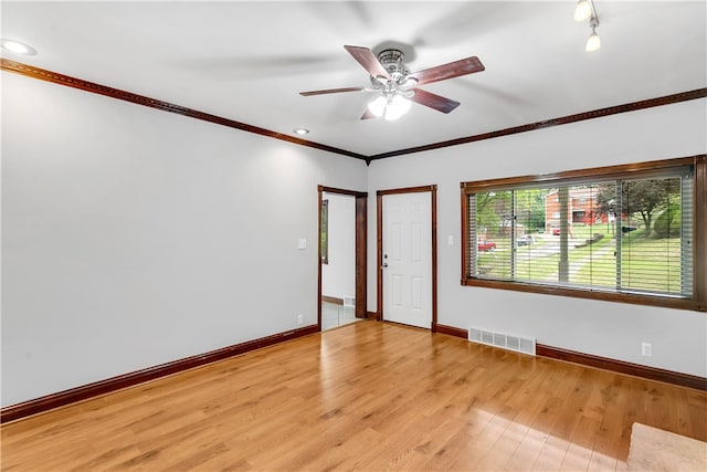 empty room with ornamental molding, light wood-type flooring, and ceiling fan