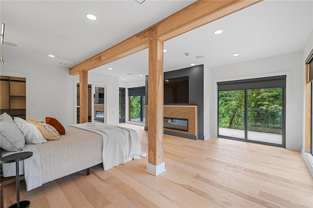 bedroom featuring beam ceiling, access to outside, and light wood-type flooring