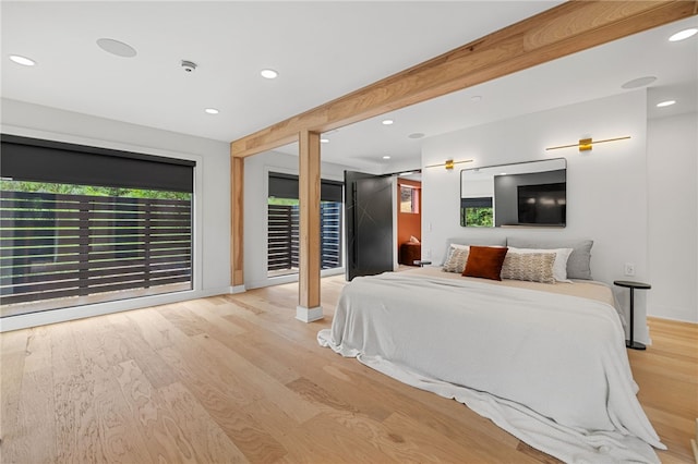 bedroom with beam ceiling, access to outside, and light wood-type flooring