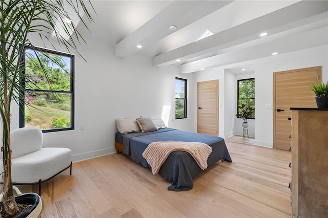 bedroom featuring beam ceiling and light hardwood / wood-style floors