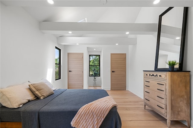 bedroom featuring lofted ceiling with beams and light hardwood / wood-style floors