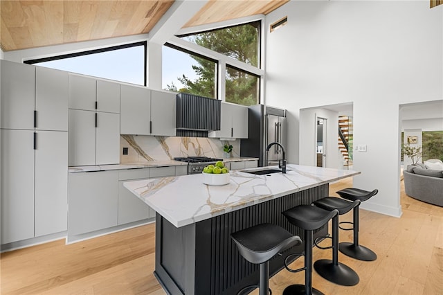 kitchen with tasteful backsplash, sink, an island with sink, and a breakfast bar