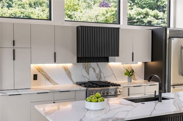 kitchen with sink, stainless steel range, light stone countertops, white cabinets, and exhaust hood