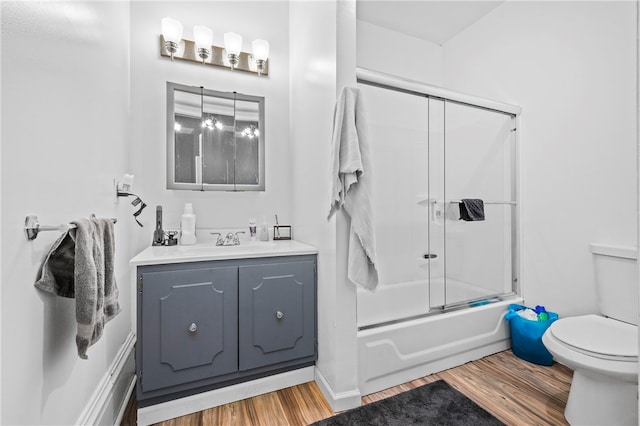 full bathroom featuring vanity, hardwood / wood-style flooring, bath / shower combo with glass door, and toilet