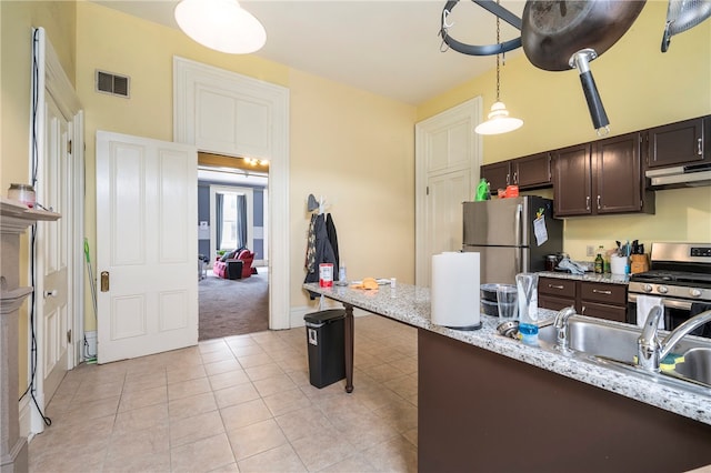 kitchen with dark brown cabinetry, appliances with stainless steel finishes, hanging light fixtures, and light colored carpet