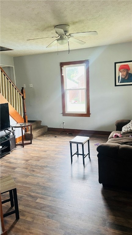 living room featuring wood-type flooring, a textured ceiling, and ceiling fan