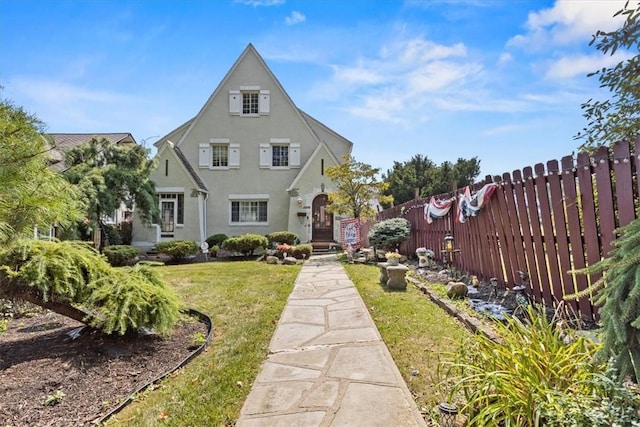 back of house featuring a lawn, fence, and stucco siding