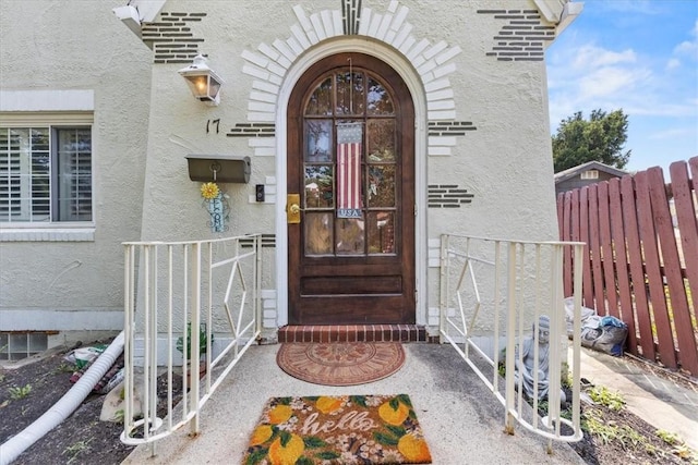 property entrance featuring fence and stucco siding