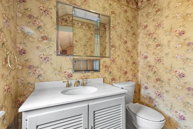 half bath featuring toilet, wallpapered walls, and vanity