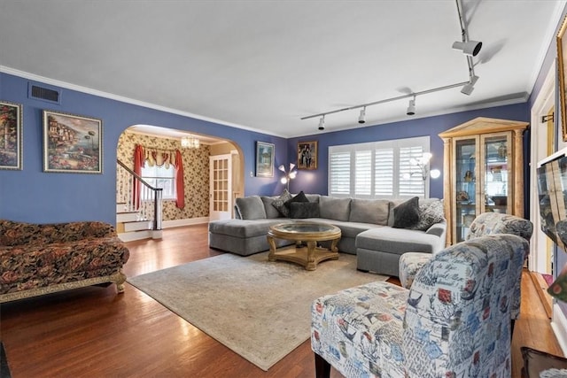 living room featuring plenty of natural light, arched walkways, stairway, wood finished floors, and crown molding