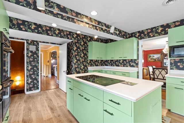 kitchen with wallpapered walls, a center island, light countertops, black appliances, and green cabinetry