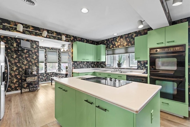 kitchen featuring light countertops, a kitchen island, black appliances, and wallpapered walls