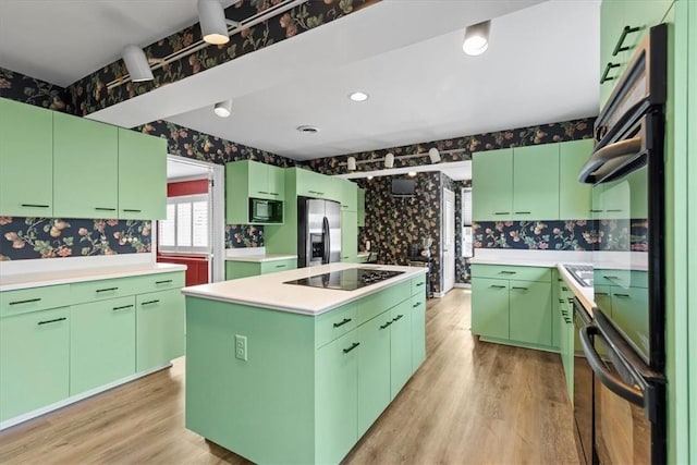 kitchen featuring wallpapered walls, a kitchen island, light countertops, black appliances, and green cabinets