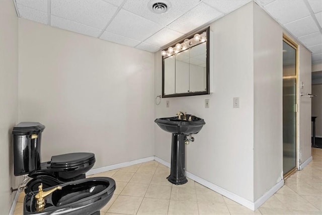 full bath featuring a drop ceiling, toilet, visible vents, baseboards, and tile patterned floors