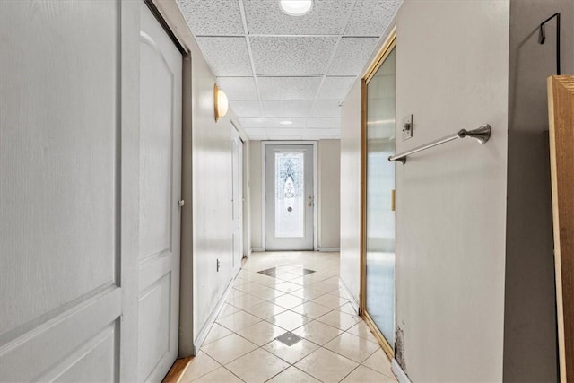 corridor featuring a paneled ceiling and light tile patterned flooring