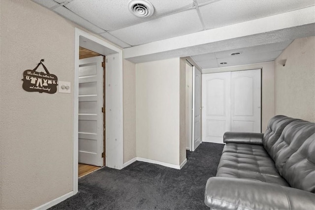 living room featuring dark colored carpet, a drop ceiling, visible vents, and baseboards