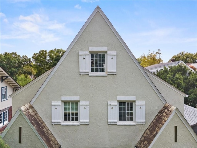 rear view of house featuring stucco siding