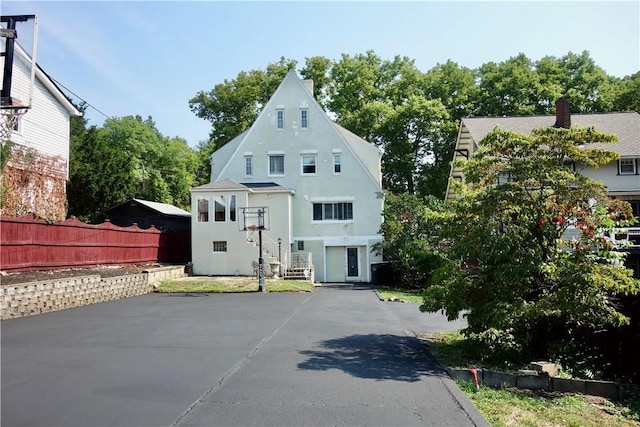 view of front facade with driveway, fence, and stucco siding