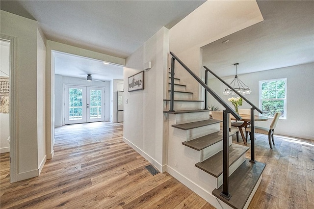 stairway with french doors and wood-type flooring