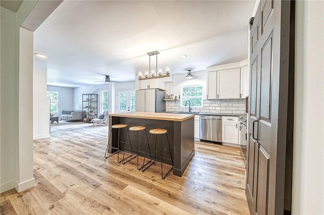 kitchen with a kitchen island, appliances with stainless steel finishes, wood counters, tasteful backsplash, and white cabinetry