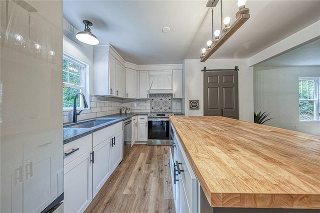 kitchen featuring sink, wooden counters, stainless steel appliances, white cabinets, and a barn door