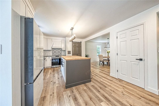 kitchen featuring pendant lighting, a center island, tasteful backsplash, white cabinets, and wood counters