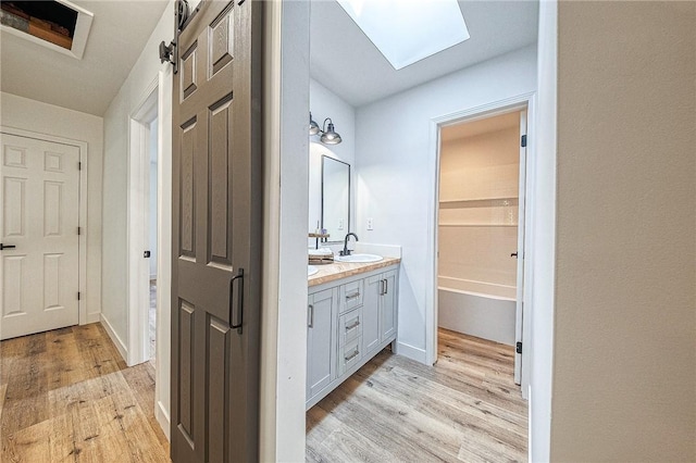 bathroom featuring hardwood / wood-style flooring, vanity, and a skylight