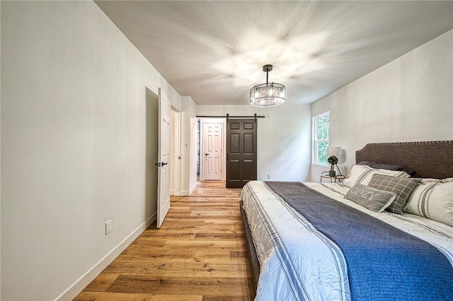 bedroom featuring a barn door and light hardwood / wood-style flooring