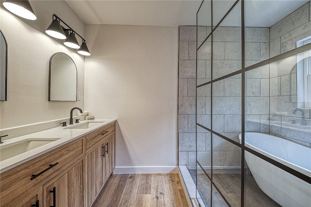 bathroom with hardwood / wood-style flooring, vanity, and tiled shower