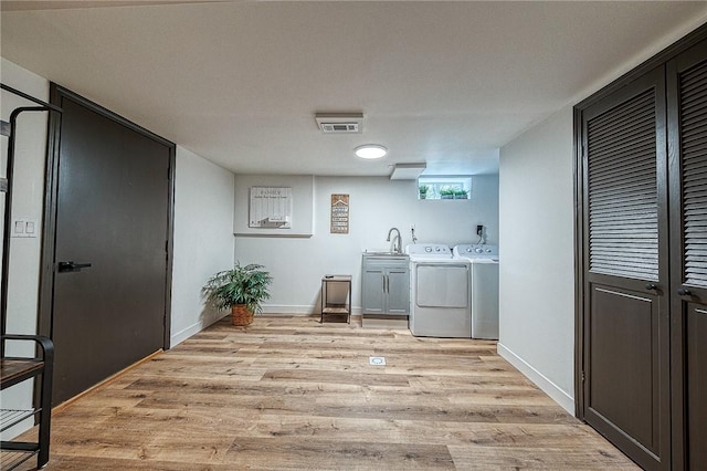 washroom with sink, washing machine and dryer, and light wood-type flooring