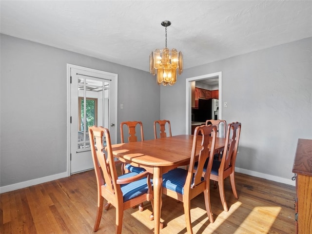 dining space featuring hardwood / wood-style floors and a chandelier