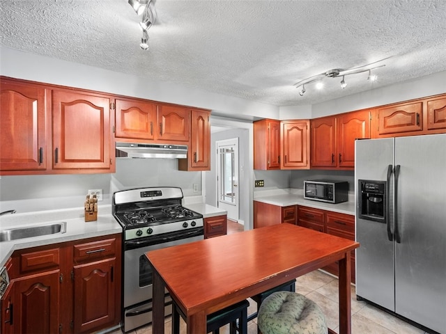 kitchen featuring sink, appliances with stainless steel finishes, a textured ceiling, light tile patterned floors, and track lighting