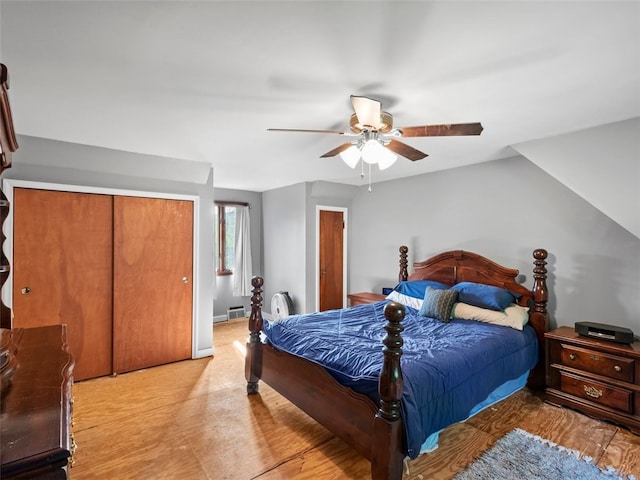 bedroom with light hardwood / wood-style flooring, a closet, ceiling fan, and vaulted ceiling