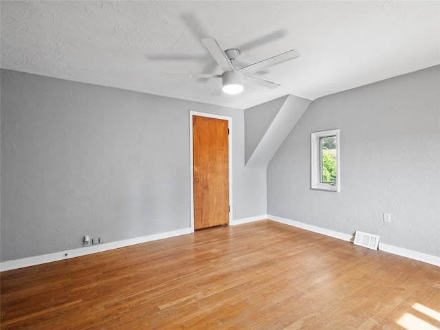 additional living space with light wood-type flooring, ceiling fan, lofted ceiling, and a textured ceiling