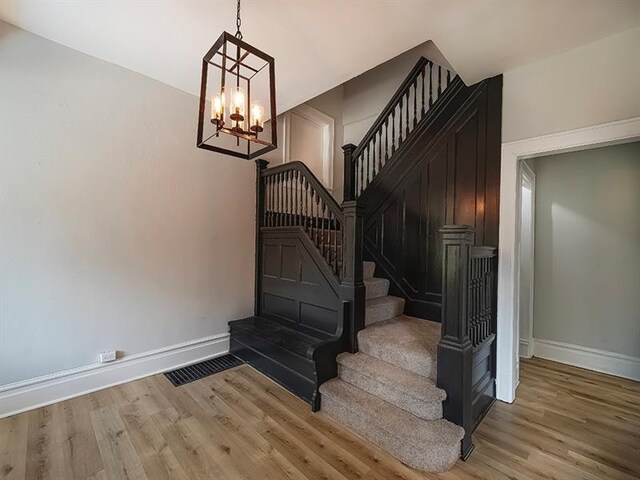 staircase with a notable chandelier and light wood-type flooring