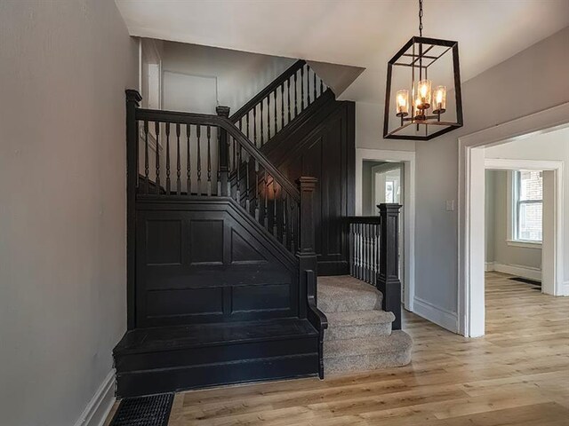 stairs featuring light hardwood / wood-style floors and a notable chandelier