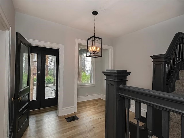 entrance foyer with a chandelier, french doors, and light hardwood / wood-style flooring