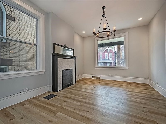 unfurnished living room featuring wood-type flooring and a chandelier