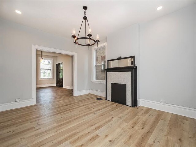 unfurnished living room featuring a notable chandelier and light hardwood / wood-style flooring