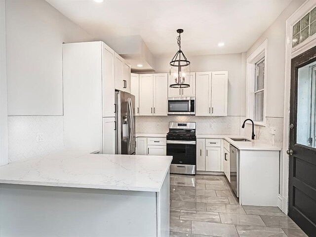 kitchen with stainless steel appliances, hanging light fixtures, sink, kitchen peninsula, and backsplash